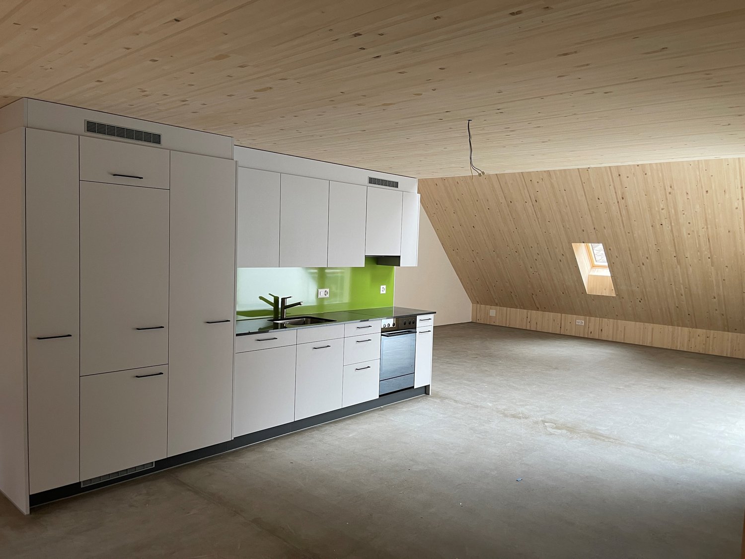 A kitchen with a white wooden ceiling, kitchen appliances, wooden panels on the walls, countertops, sinks and cabinets