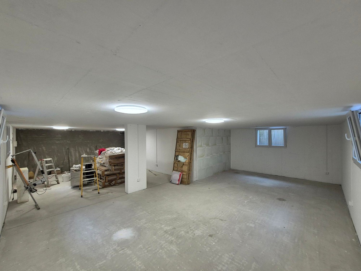 empty room with a ceiling and lights, a small white pillar, ladders and tools