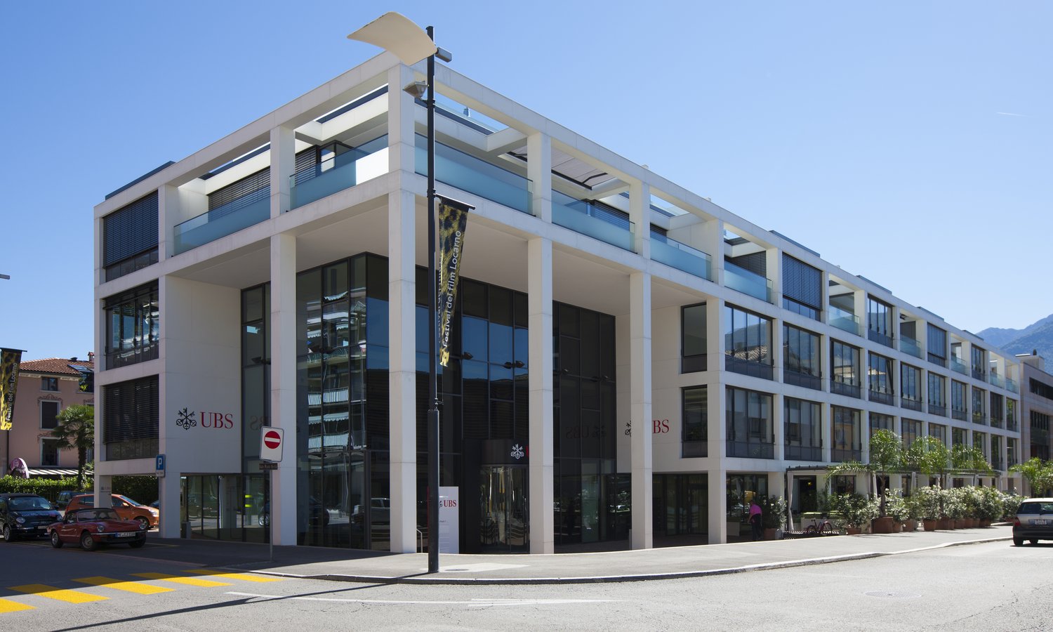 Multi-story building with glass facade, balconies, and multiple entrances