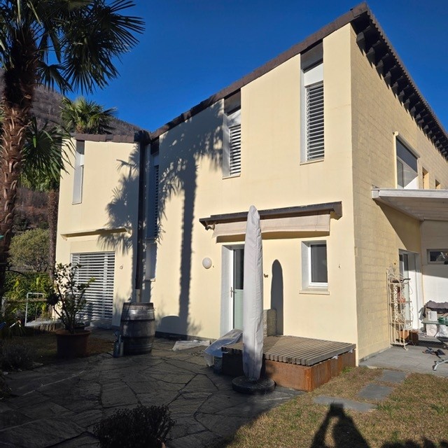 2 story house, yellow exterior, brown roof, balcony, patio, palm trees, barrel, potted plant
