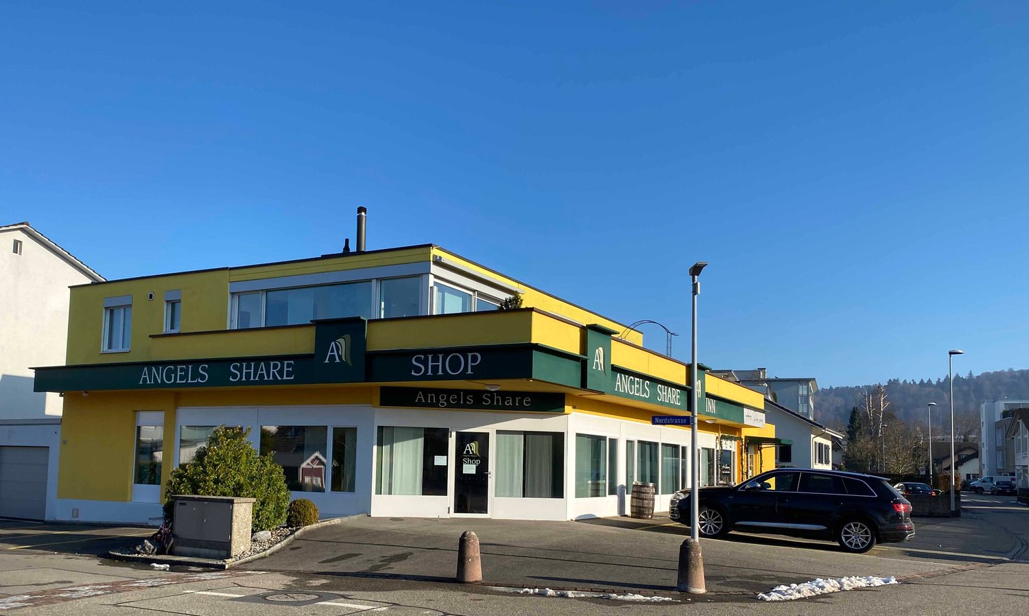 Yellow shop with sign reading 'ANGELS SHARE' on top with a large window