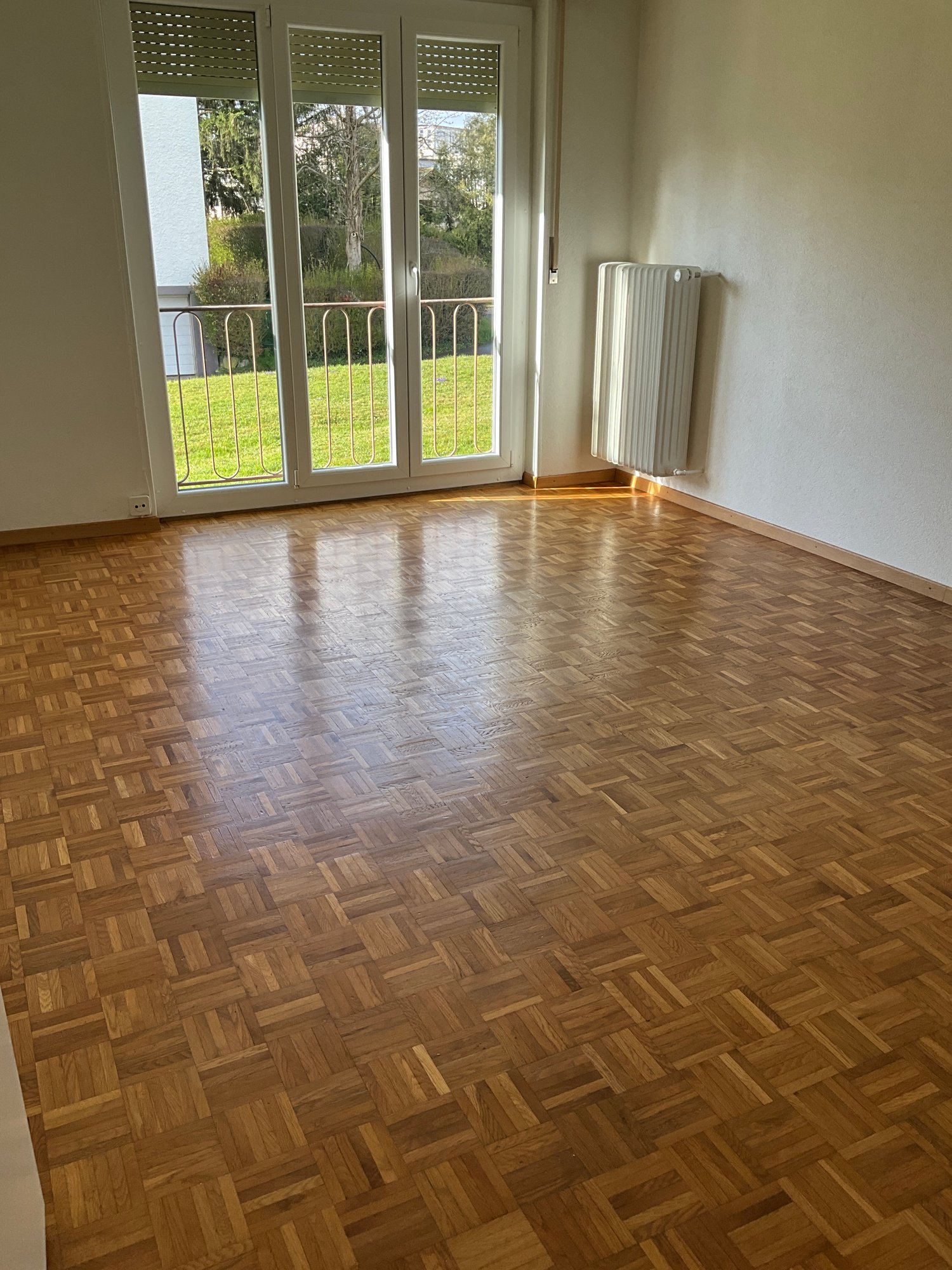 empty room, wooden parquet floor, sliding glass doors, balcony, radiator