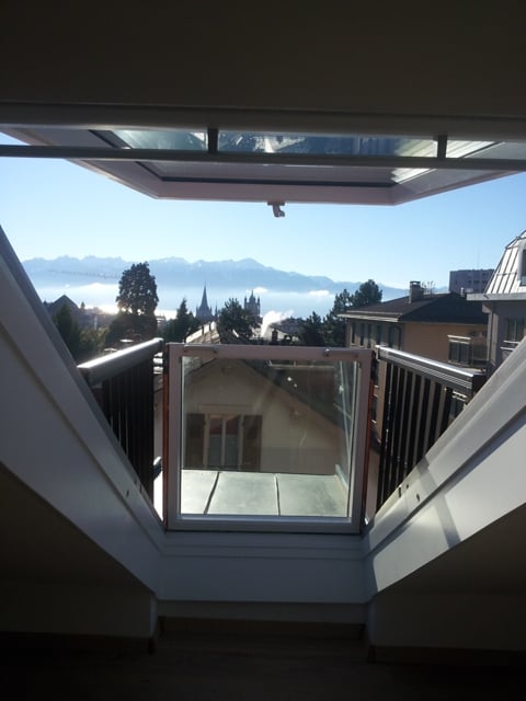 balcony with sliding glass door, black railing, view of mountains and city