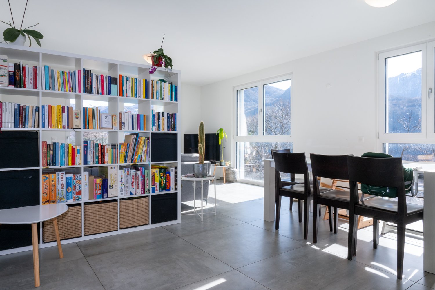 Dining area with a large bookshelf, dining table, chairs, and a view of the mountains