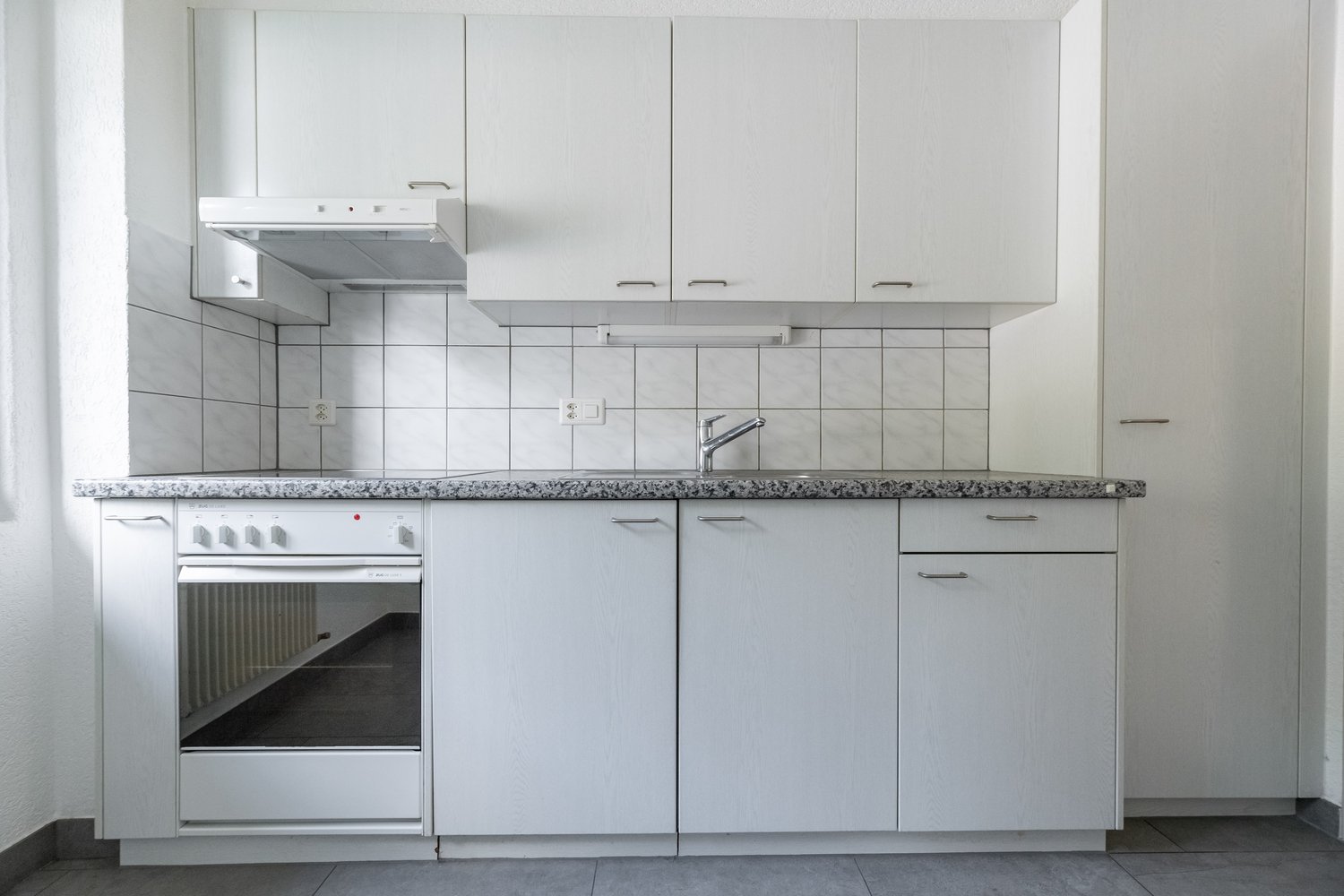 White cabinets, granite countertop, tiled backsplash, stove, dishwasher