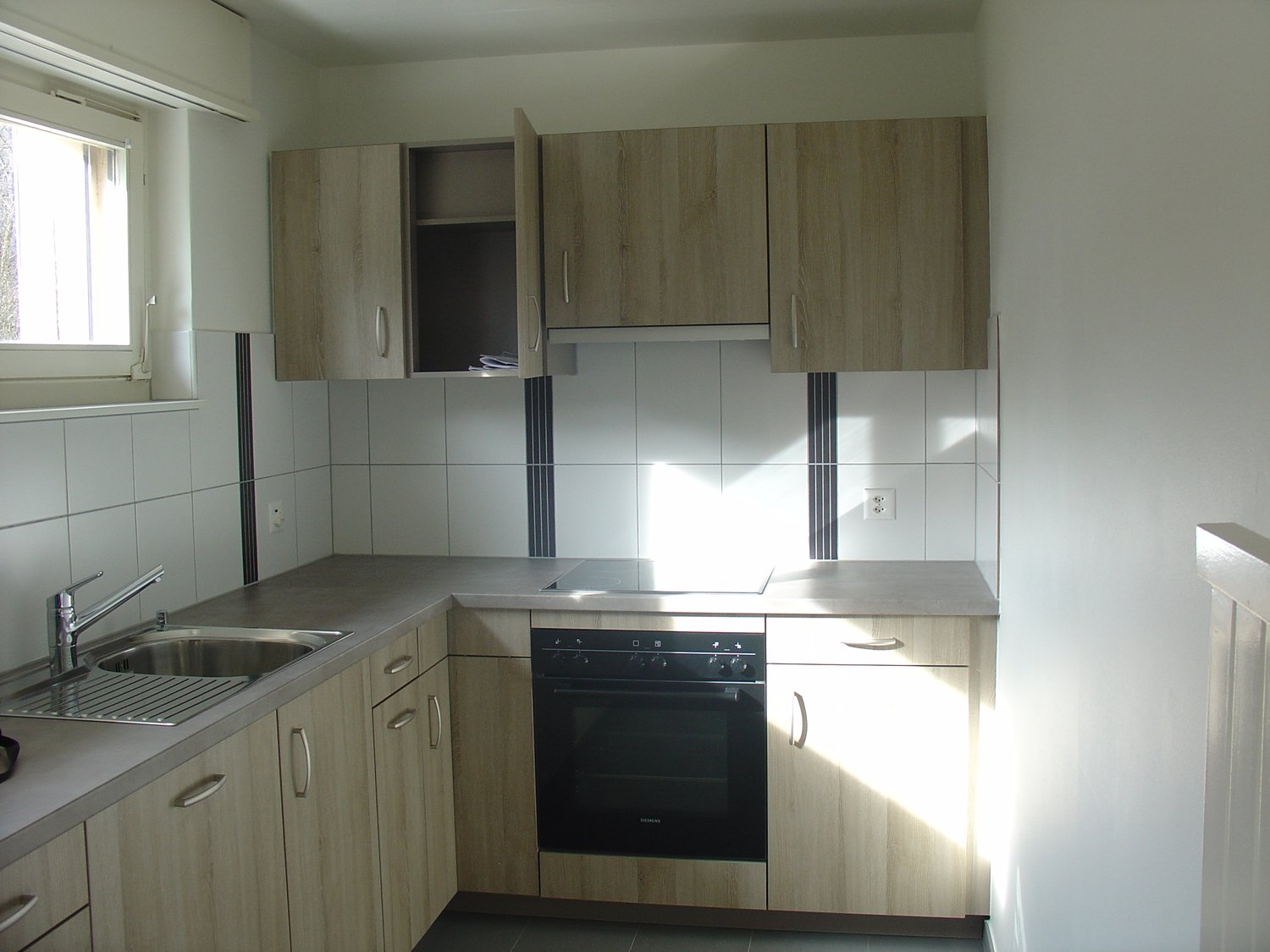 Modern kitchen, wooden cabinets, tile backsplash, integrated appliances, stainless steel sink and faucet, natural lighting