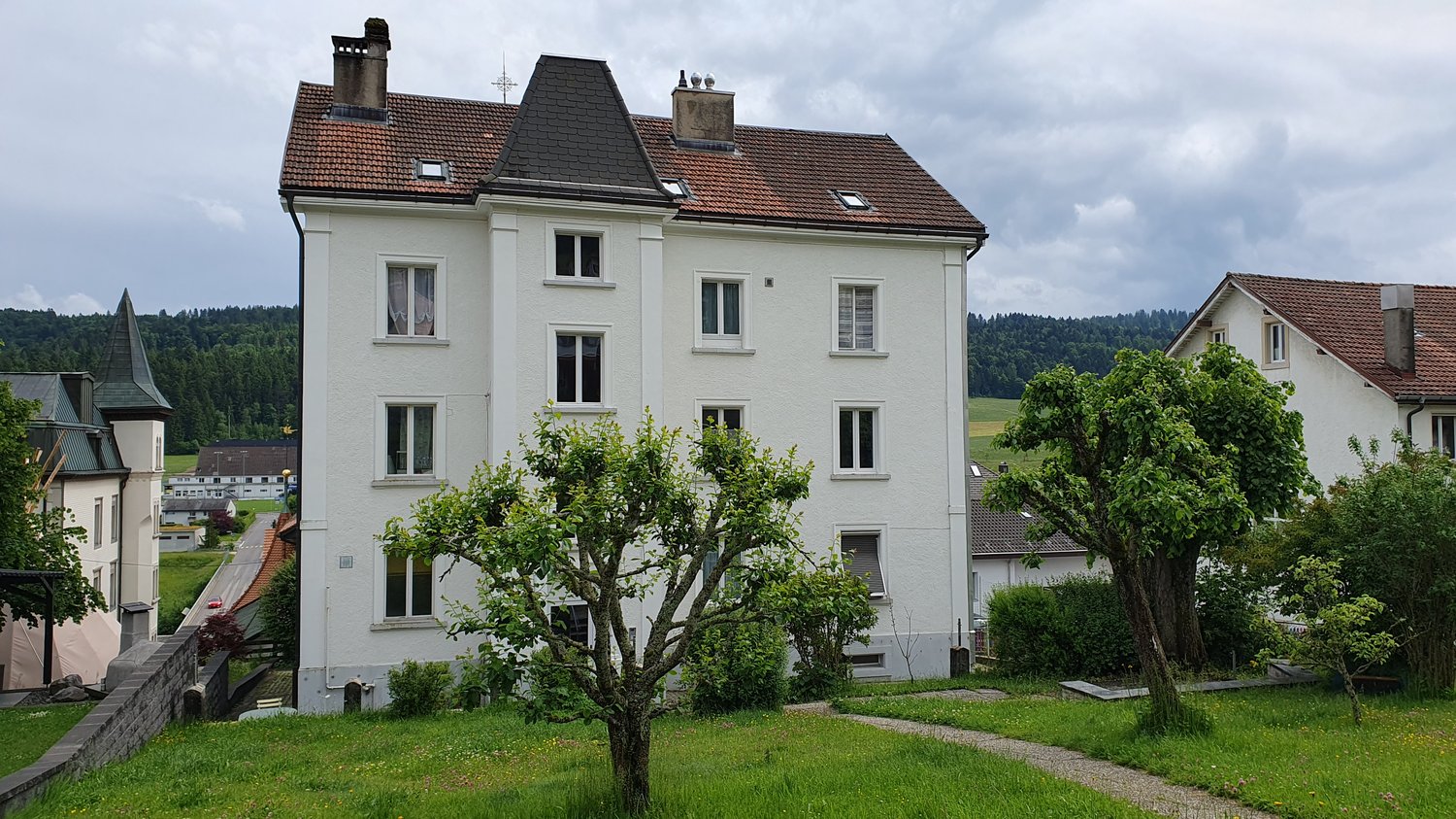 large white building, brown roof, two chimneys, many windows