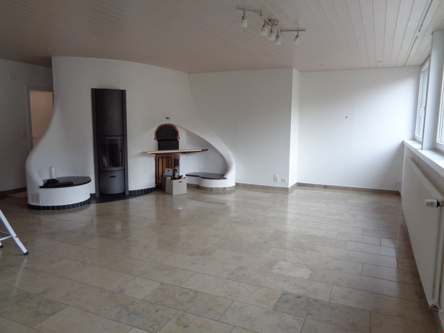 Open floor plan with white walls, tiled floor, modern fireplace, minimalistic design