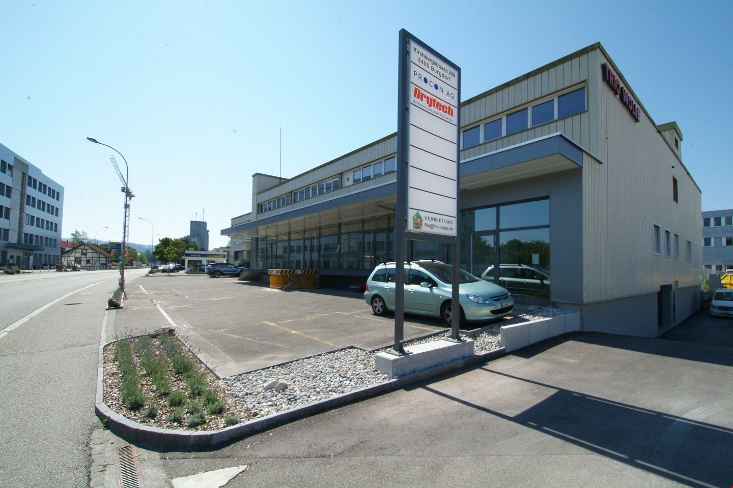 two-story building with glass windows, large parking area, modern design