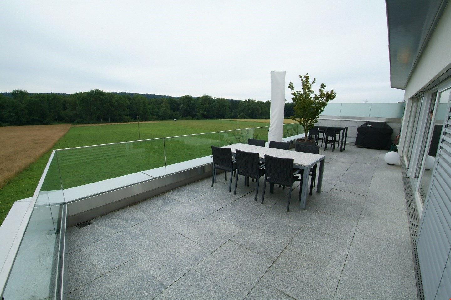 glass fence, grey tiles, glass table, seating area, open view to the outside, landscape