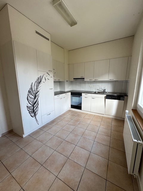 white cabinetry, tiled floor, black countertops, sink with faucet, built-in oven, dishwasher, washing machine sticker