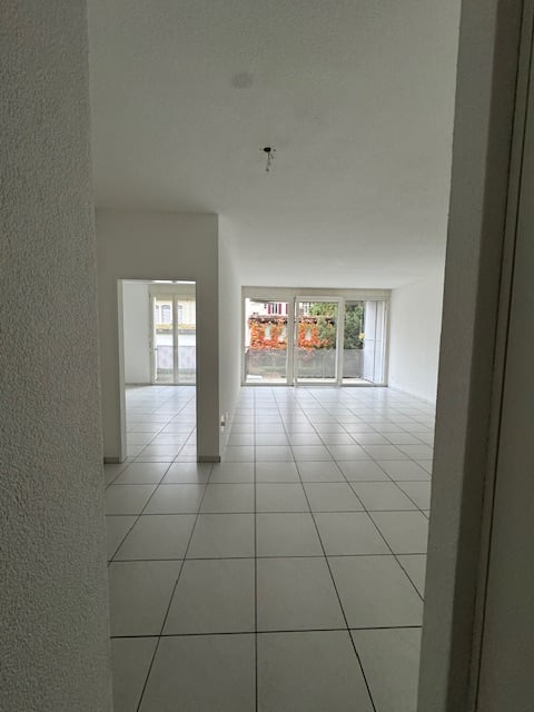 empty room, large window, white floor tiles, white walls, doorway, glass door leading to balcony