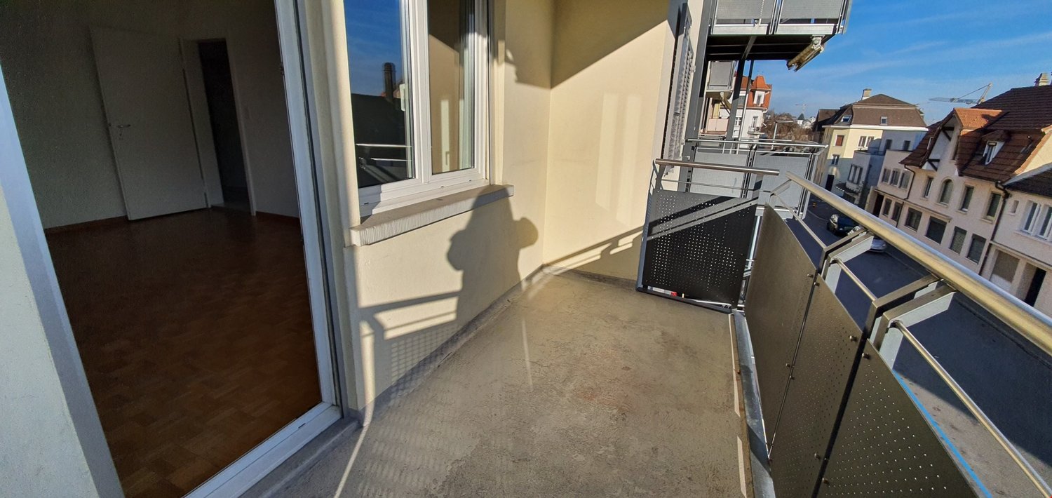 Balcony with wooden floors, large window, view of street and buildings