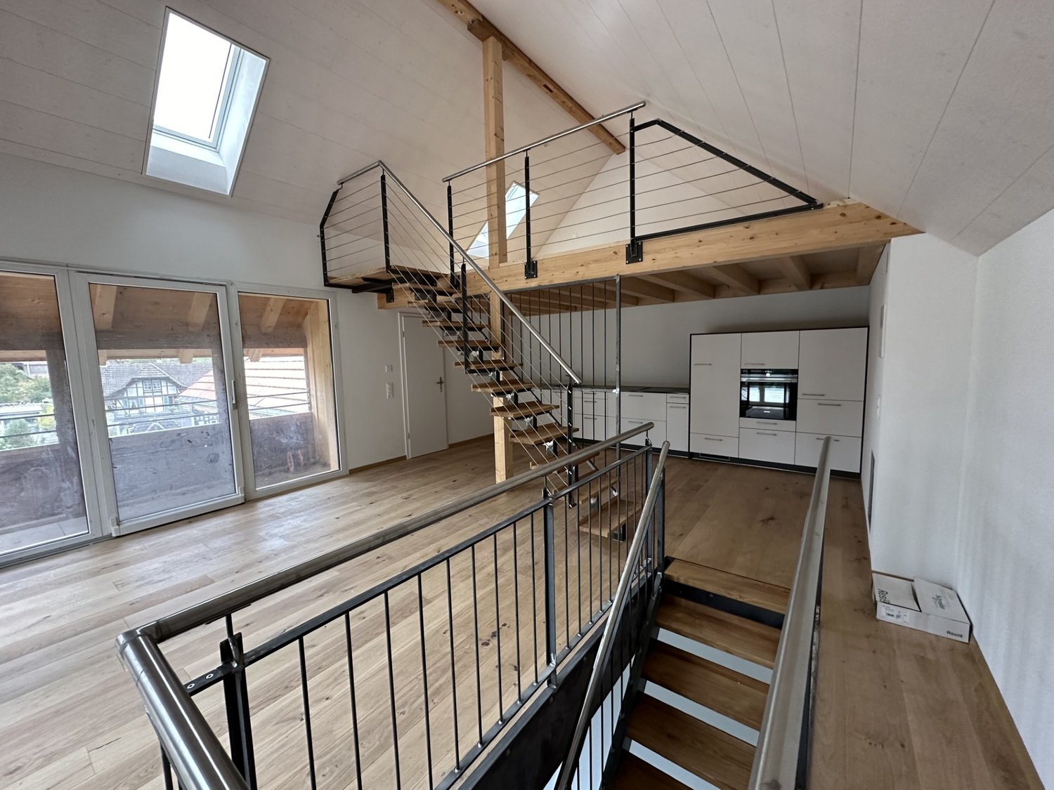 wooden floors, skylight, white walls, metal handrails, stairs, kitchen