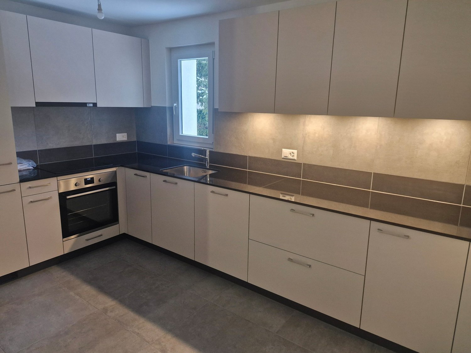 modern kitchen with built-in appliances, granite countertops, grey tiled flooring, overhead lighting