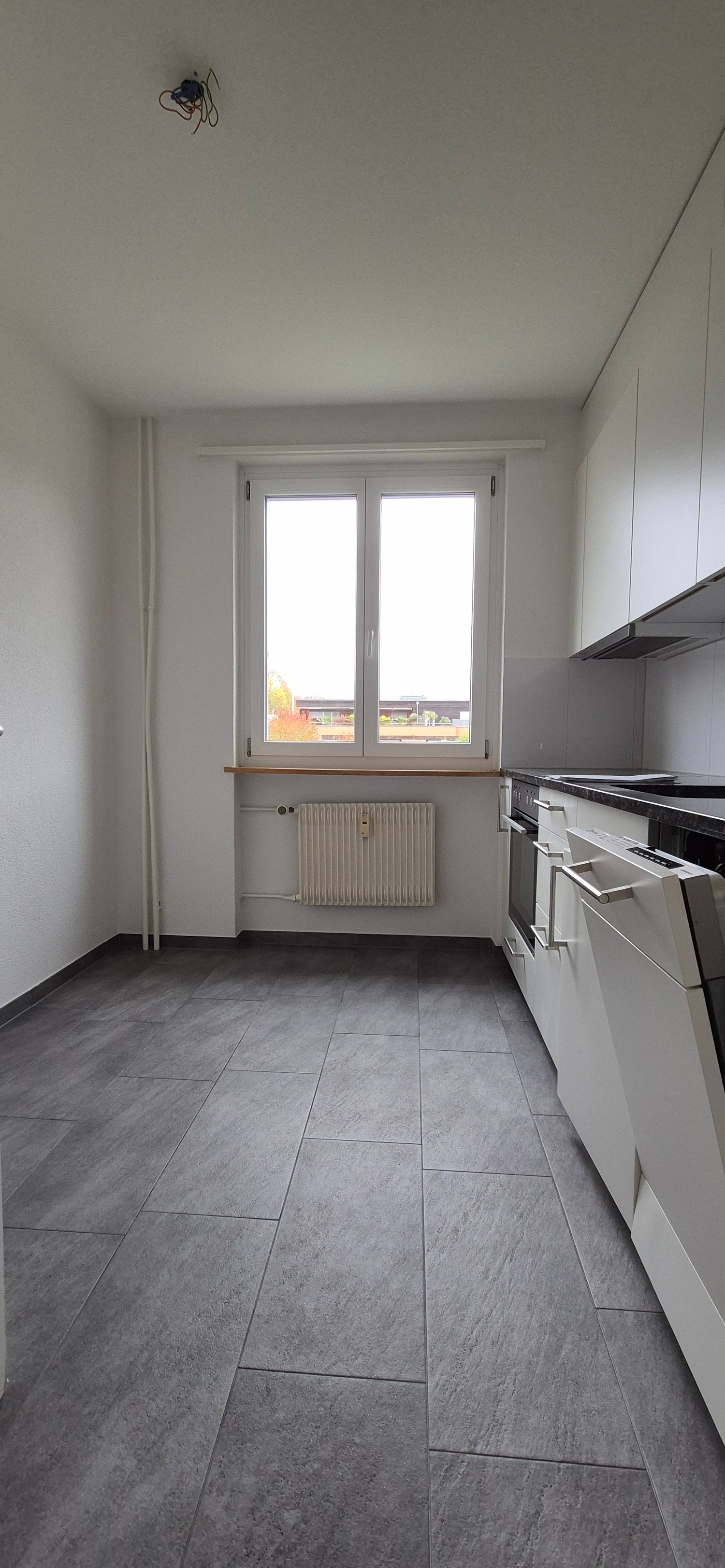 kitchen with gray tiles, modern kitchen appliances, white cabinets, window