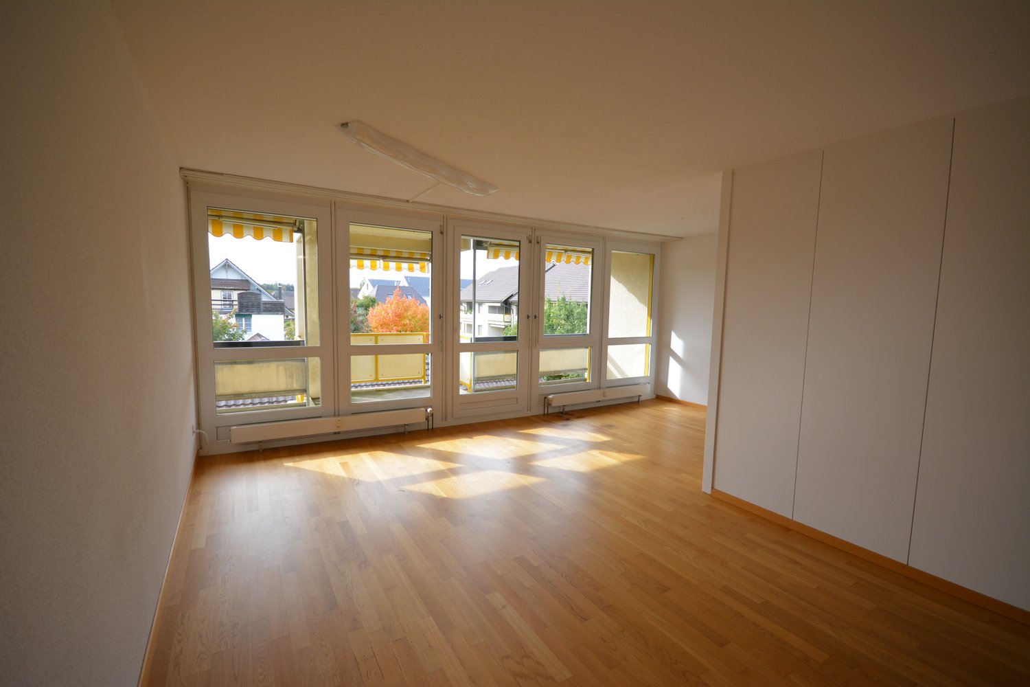 Hardwood floors, large windows with balconies, white cabinets, neutral color walls