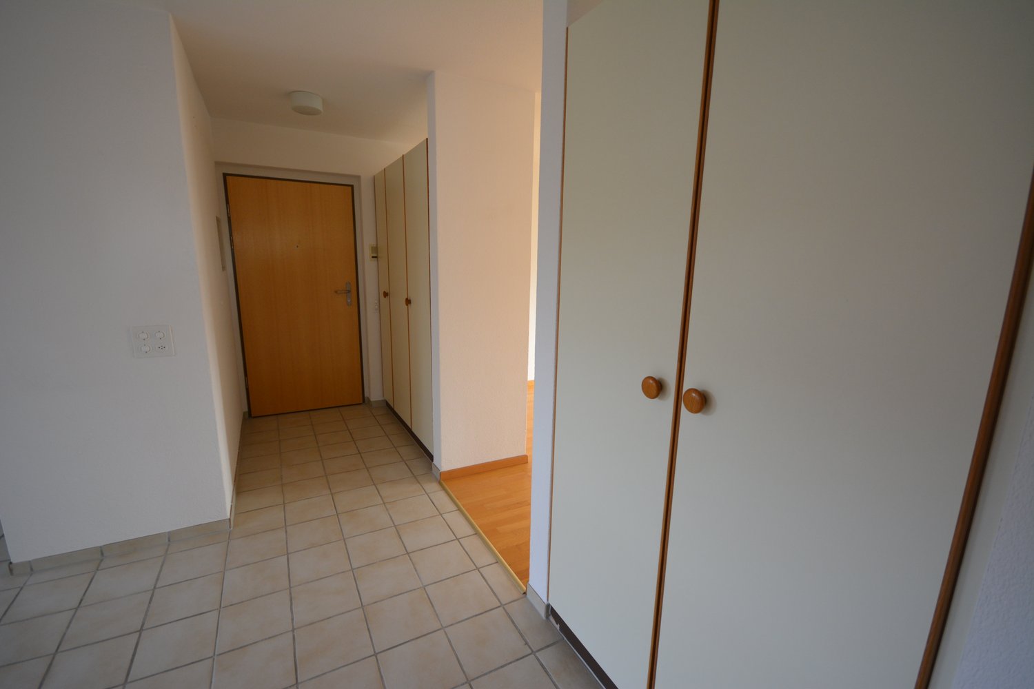 tiled floor, wooden floor at room entrance, two doors on right, a door leading to another room on left