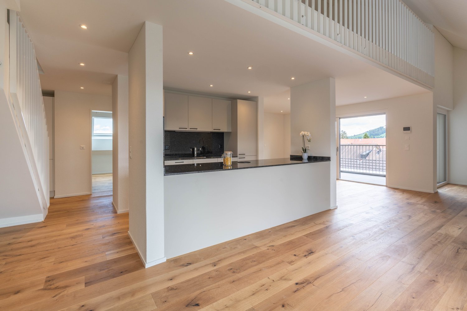 Kitchen with balcony, white cabinets, black countertops, open shelving, potted plant, open staircase