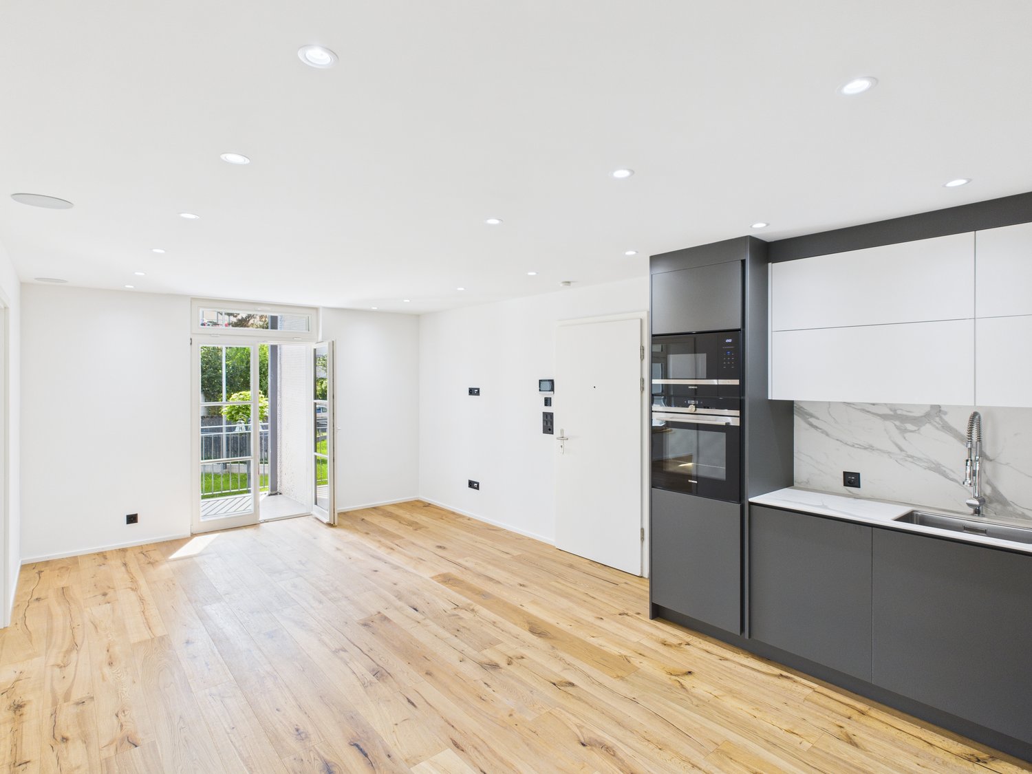 empty room, wooden floors, white walls, glass door, open balcony, marble countertop, sink, faucet