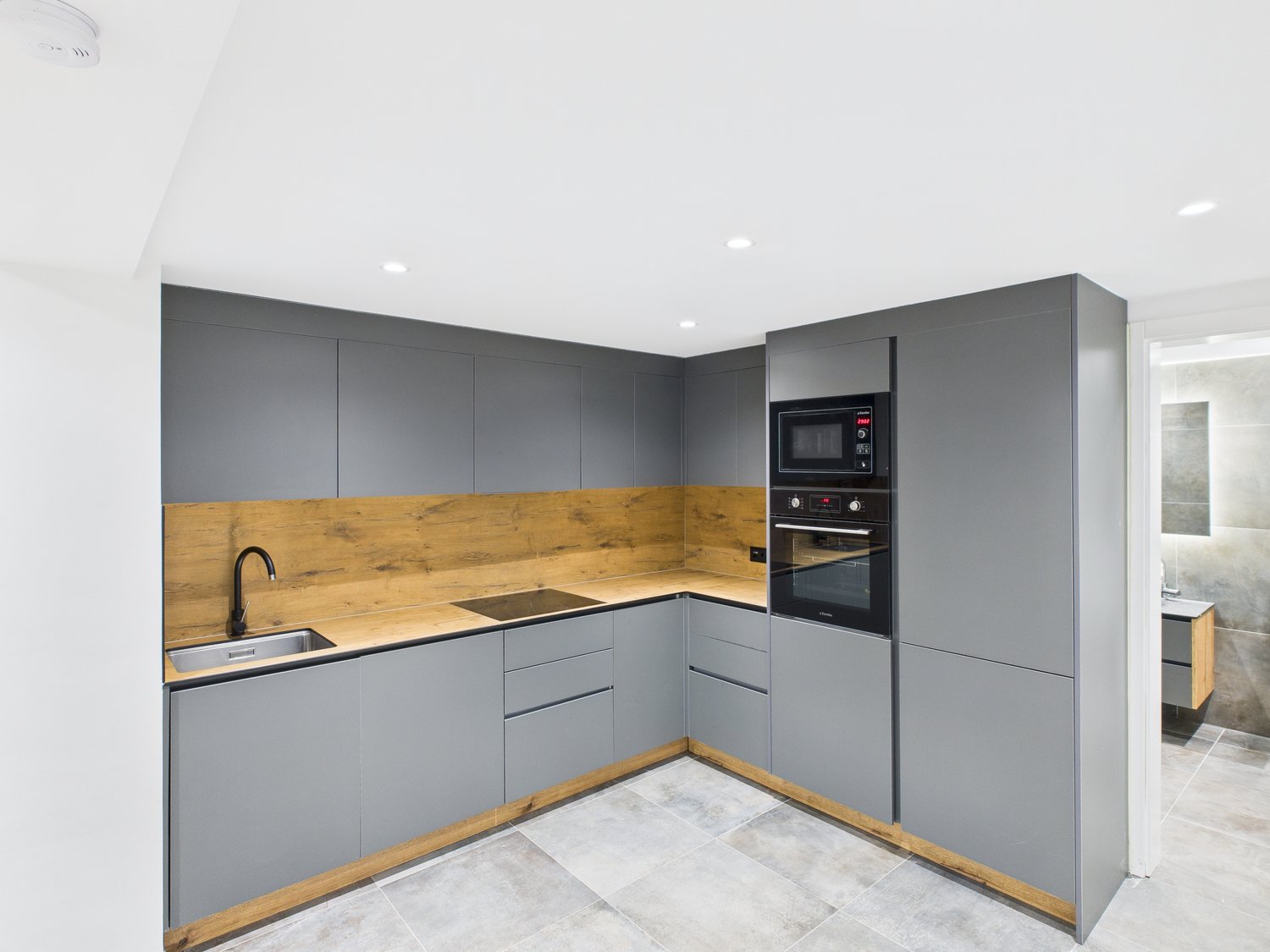 Gray cabinets, wooden countertops, integrated microwave and oven, modern faucet, tiled flooring