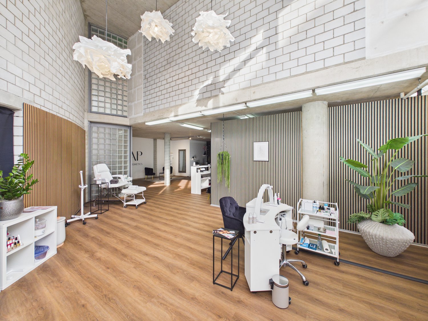 Interior design with white walls, wooden floor, multiple white chairs, lamps, desk, plants