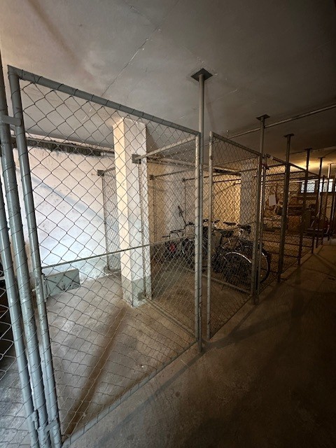 Metallic cage, parked bicycles, concrete floor