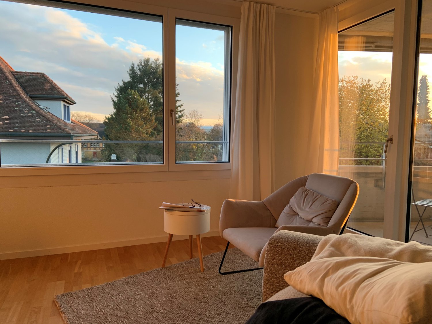 living room with windows, wooden floor, two-seater sofa, side table, rug, balcony with view