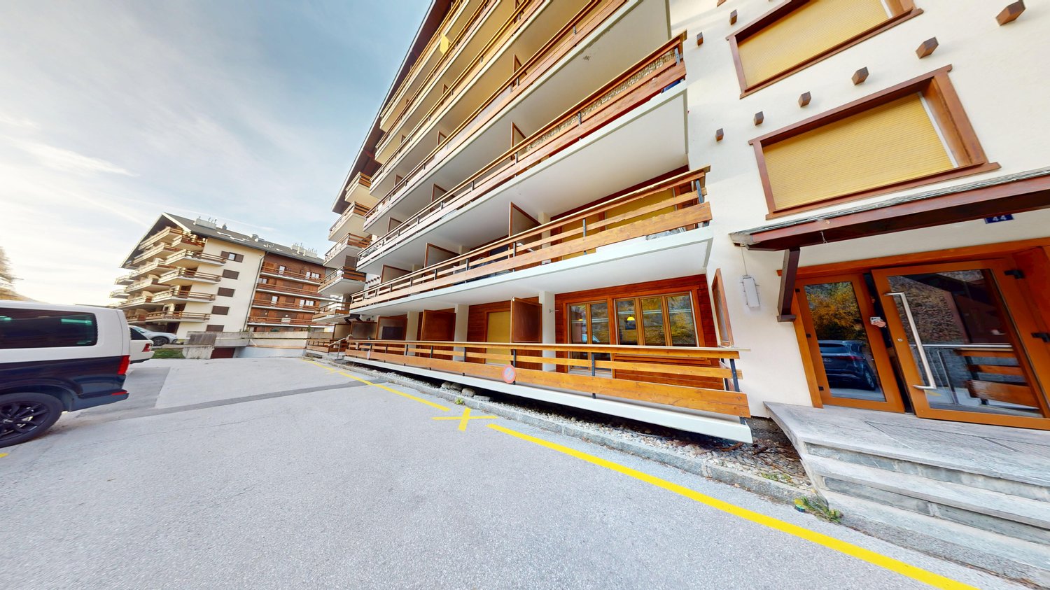 Large apartment building, several balconies, stairs leading to the entrance