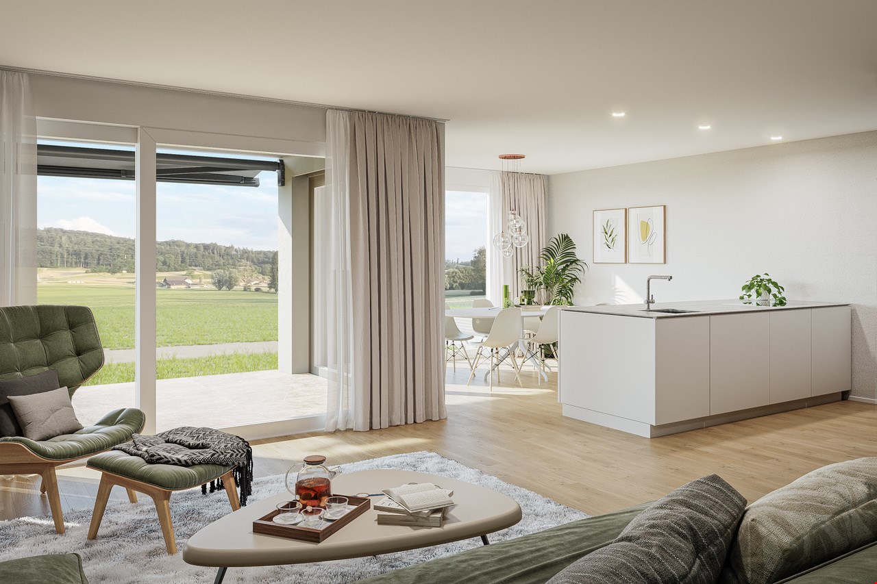 Spacious open-plan living room with large windows offering a scenic view of the countryside, hardwood floors, white walls, gray curtains, green upholstered furniture, coffee table, and a modern kitchen area with white cabinets and countertops