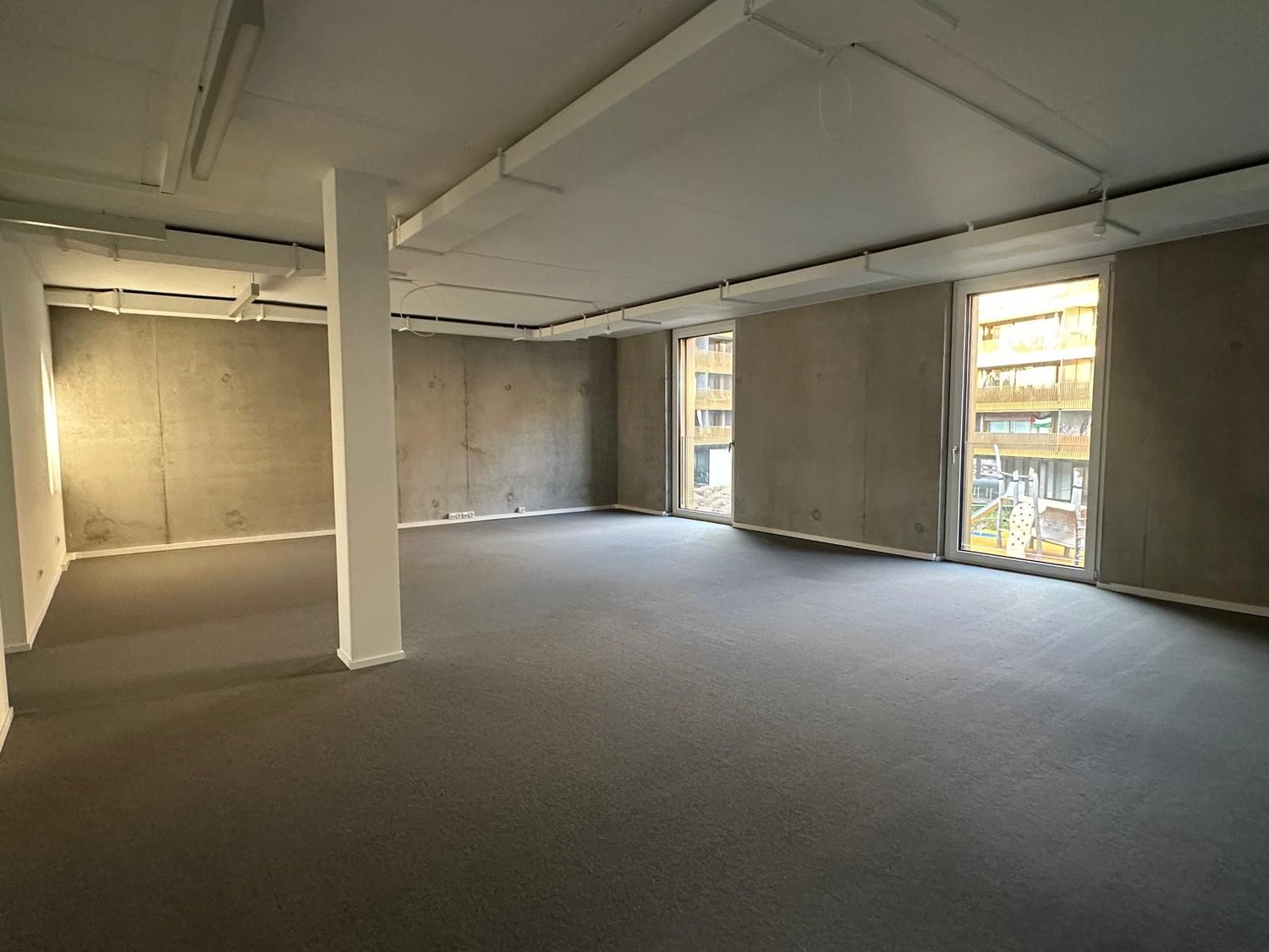 empty room, concrete walls, glass windows, gray carpet