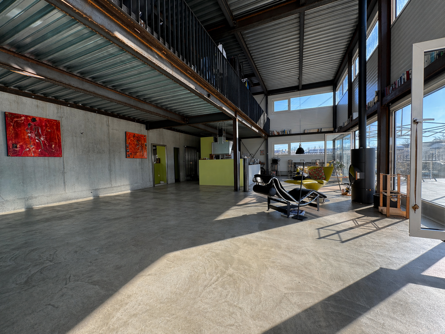 large open space, concrete floor, metal ceiling, large windows, modern furniture, artwork on wall
