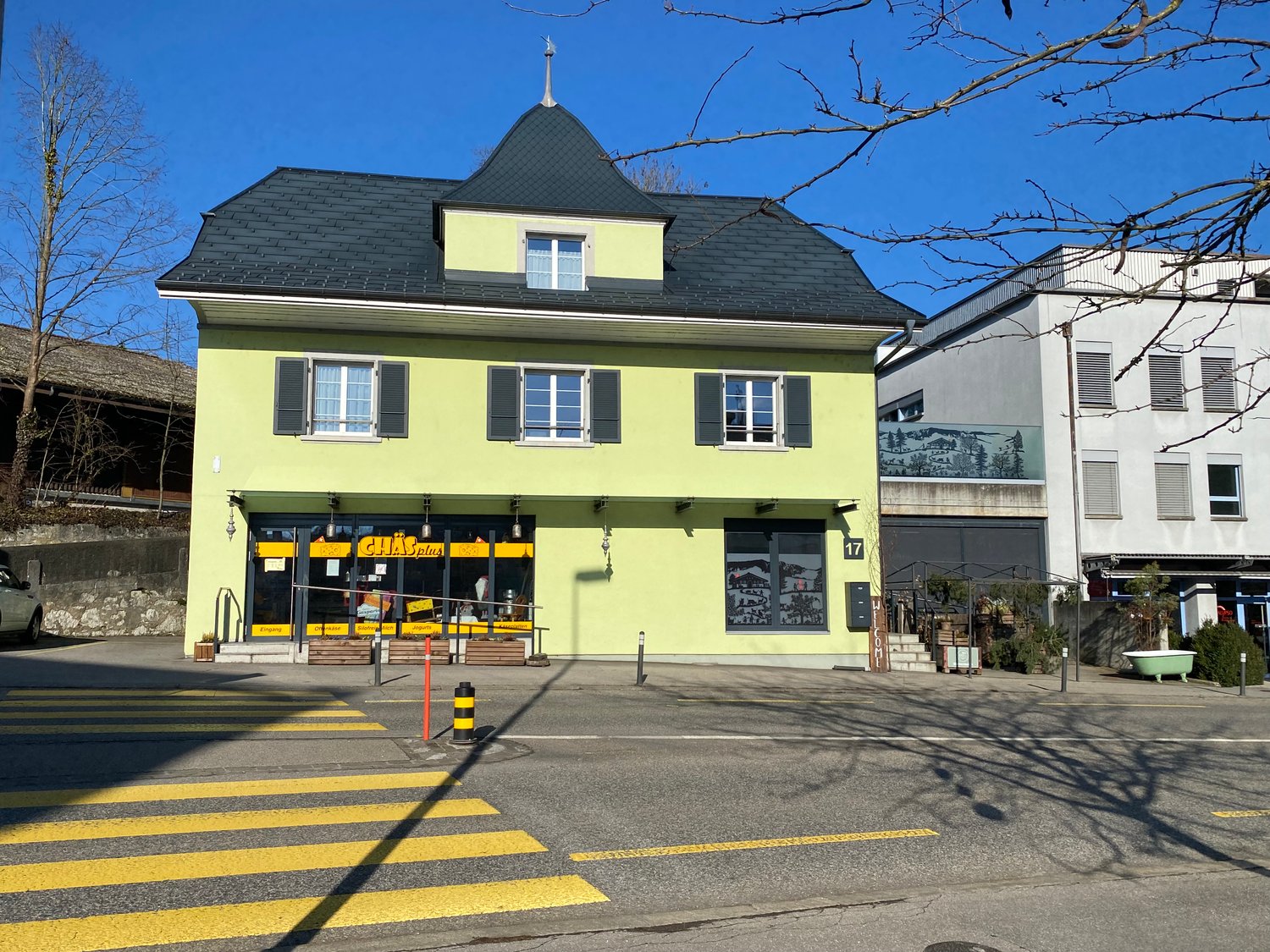 3 story building, yellow exterior, black roof, glass doors, windows, street view