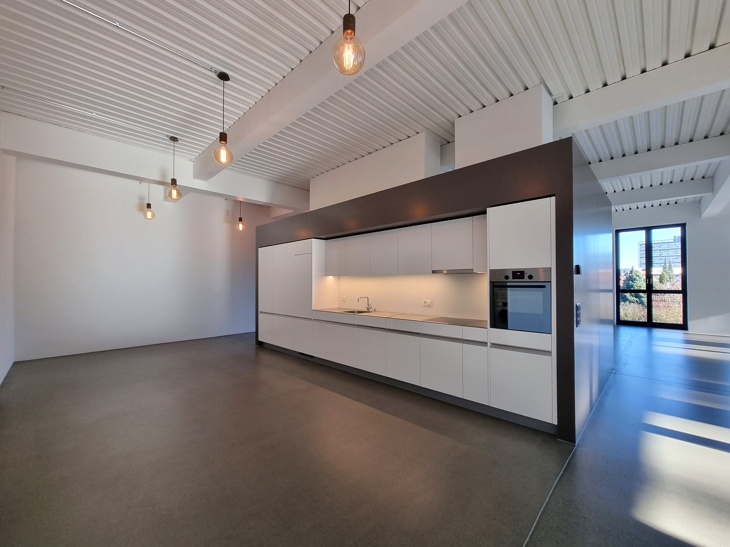 Modern kitchen with white cabinets, stainless steel appliances, open layout, large windows with city view