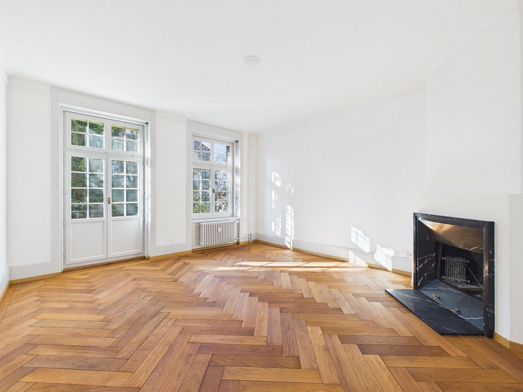 empty room, white walls, wooden parquet floor, fireplace, windows, radiator