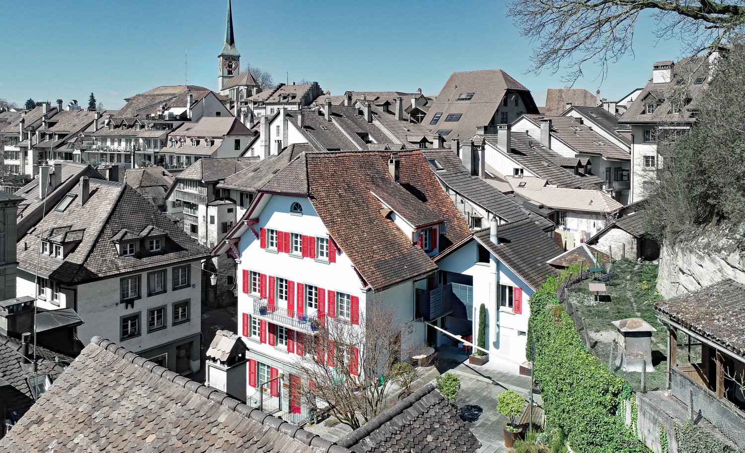 House with red shutters, brown roof, balconies, located in the city of Bern, Switzerland, surrounded by other houses