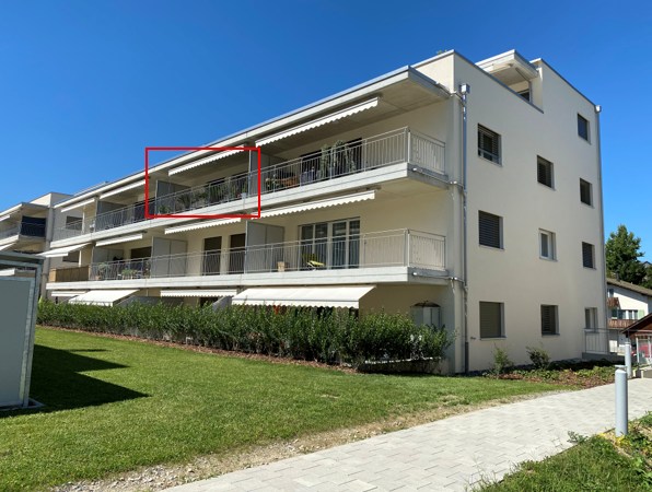 White apartment building, multiple balconies, well-maintained garden, paved walkway