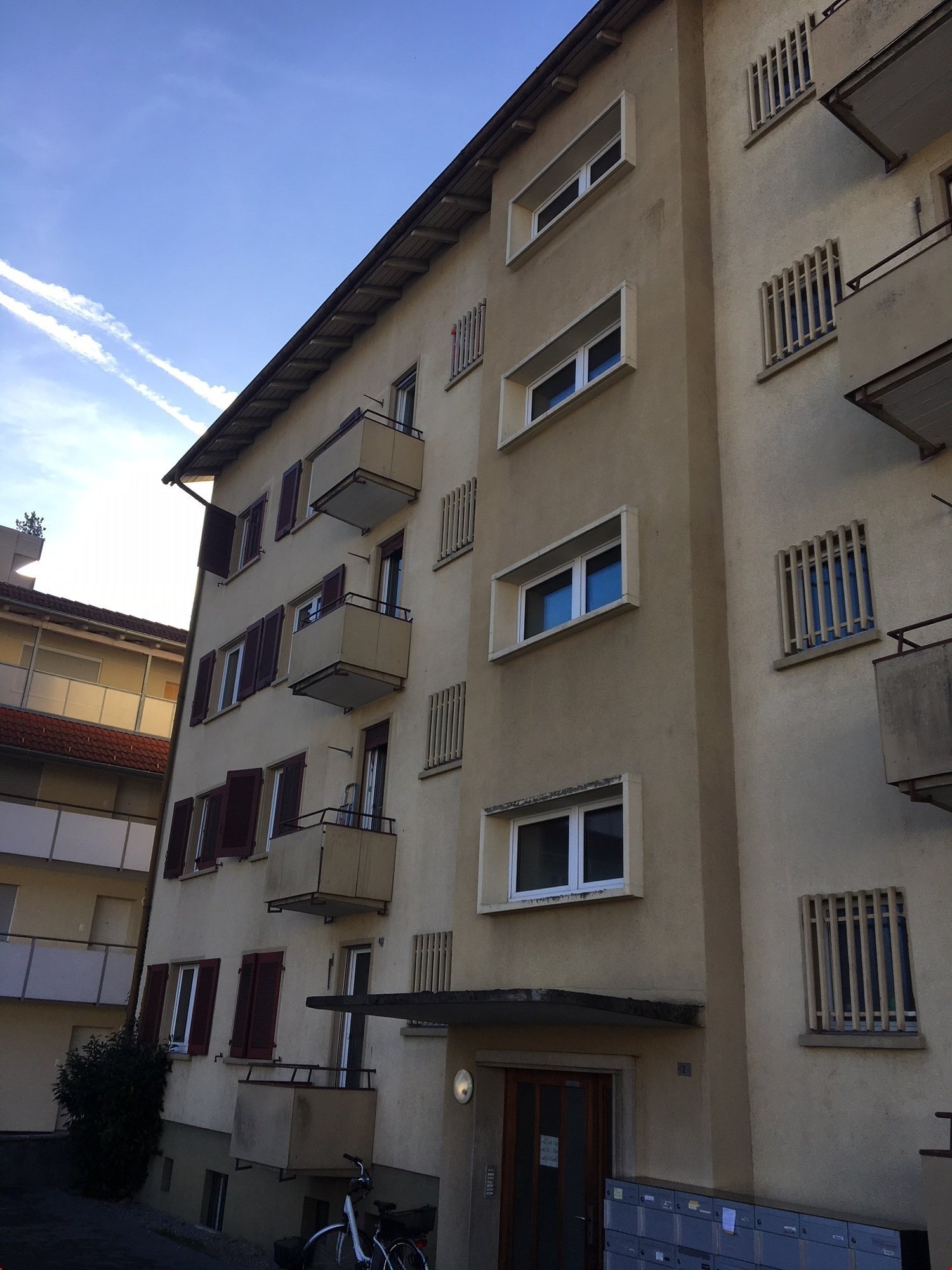 Multi-story apartment building with beige exterior, balconies, and windows. The building appears to have several floors and units.