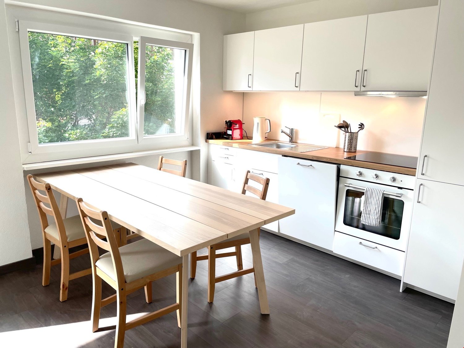 kitchen with dining area, table, chairs, white cabinets, gas stove, oven, sink, window with view of trees