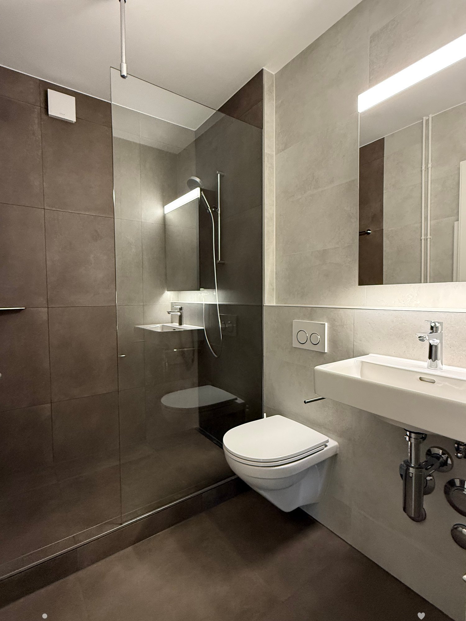 Modern bathroom with walk-in shower, toilet, and vanity with sink.