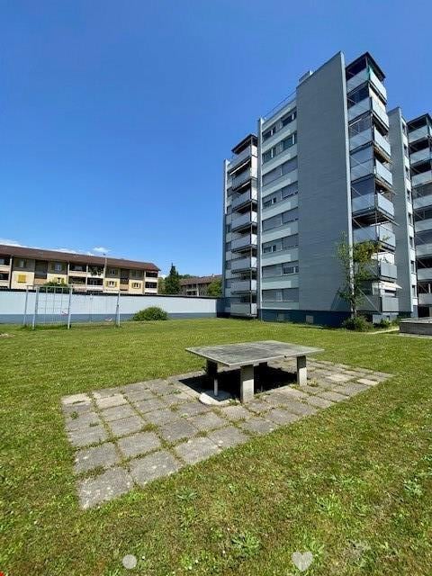 Large grassy area with a small concrete table in front of a multi-story building