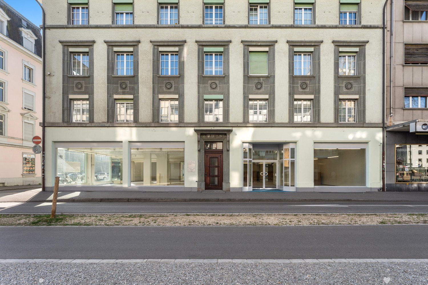 3 story building, multiple windows, glass doors, brown door, concrete sidewalk