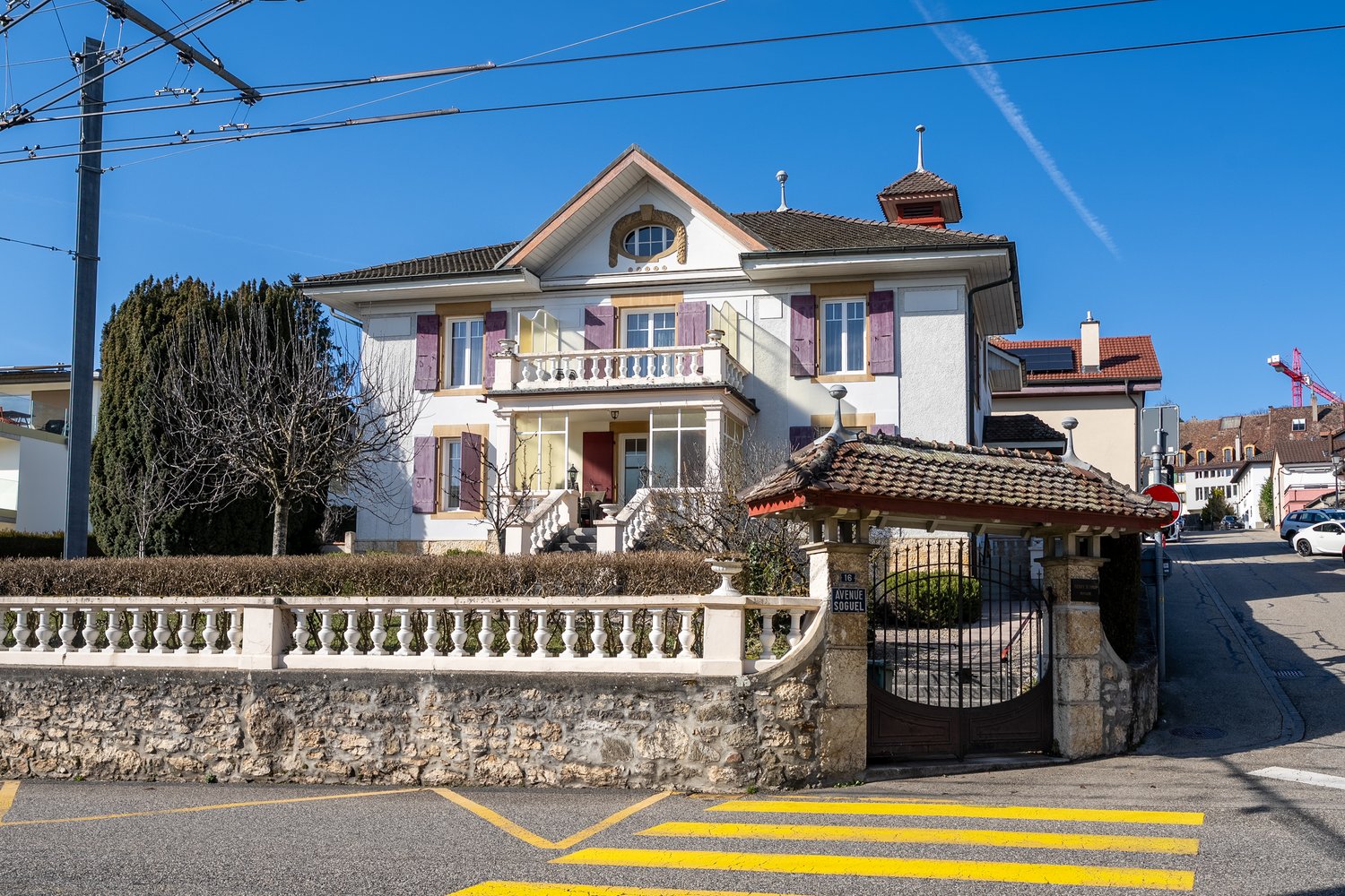 2 story house, multiple windows, balcony, stone fence, gate, no visible garage or pool