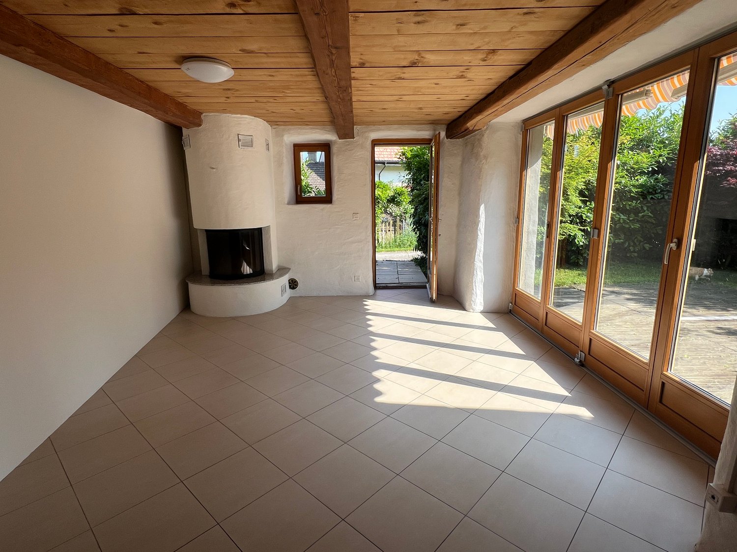 room with fireplace, tile floor, wooden beams, sliding glass doors, white walls, recessed lighting