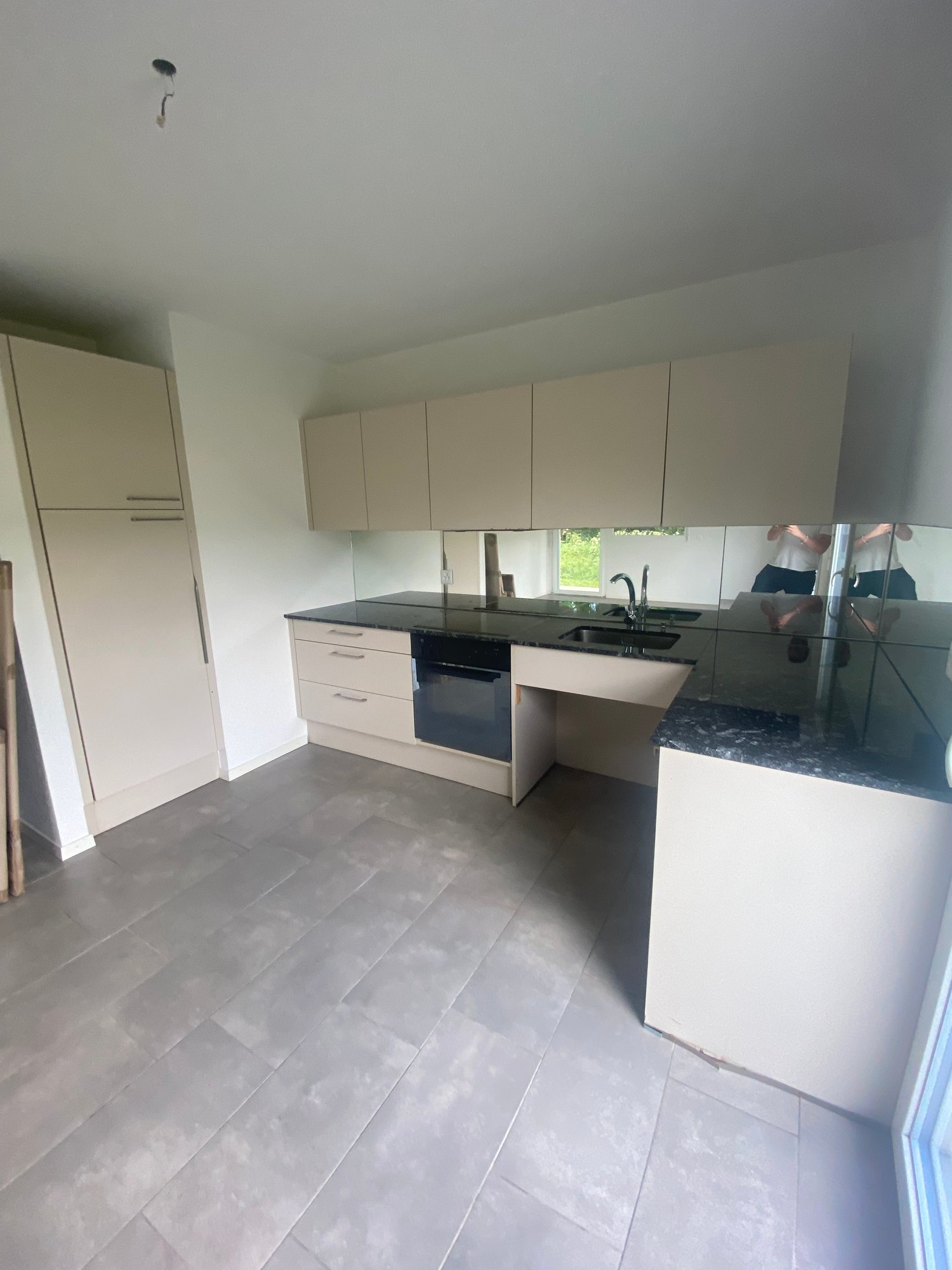 modern kitchen with white cabinets, black countertops, stainless steel sink, faucet, dishwasher, tiled floor