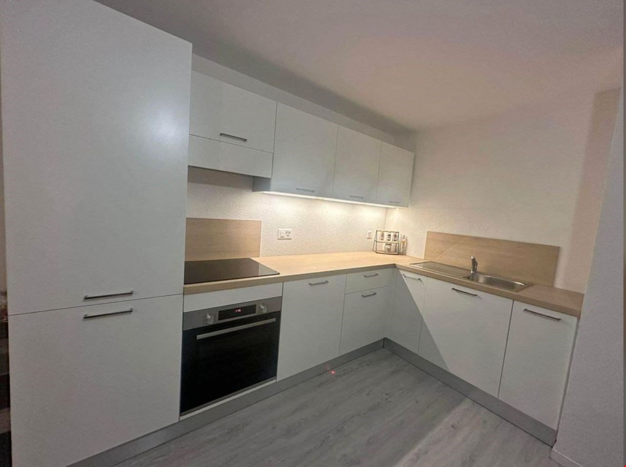 modern kitchen with white cabinets, wooden countertops, integrated oven and dishwasher, sink with faucet, power outlets