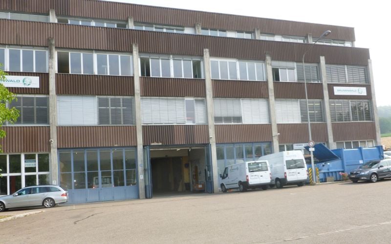 large office building, brown color, many windows, large entrance, trucks and cars parked in front