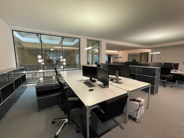 modern office space with desk, chairs, computers, large windows, tiled floor, lamps