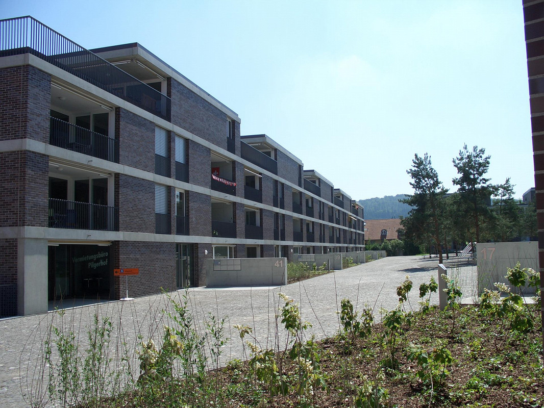 Apartment building, brick facade, multiple balconies, paved walkway, greenery