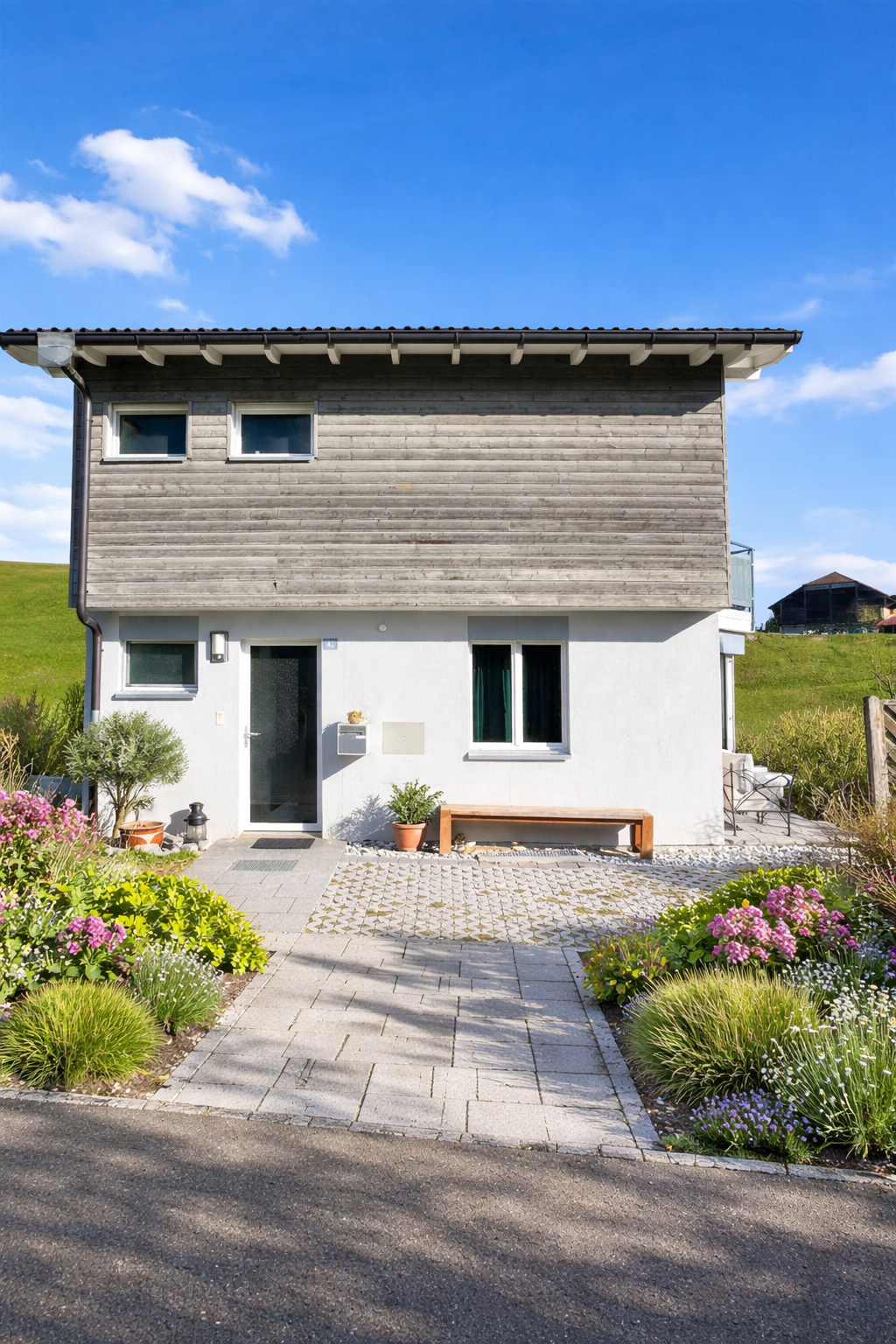 2 story house, wooden exterior, white walls, raised ground floor, garden, bench, mailbox